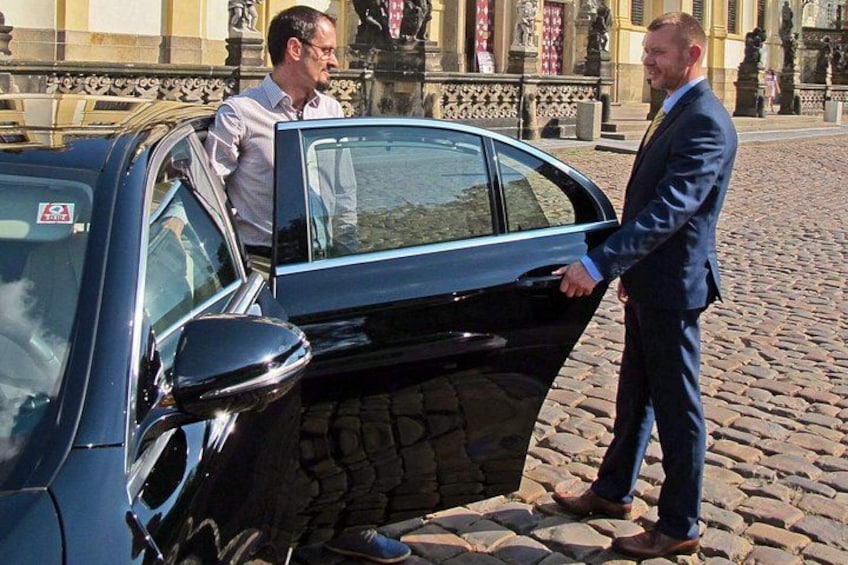Ein Mann im Anzug öffnet eine Autotür. 3