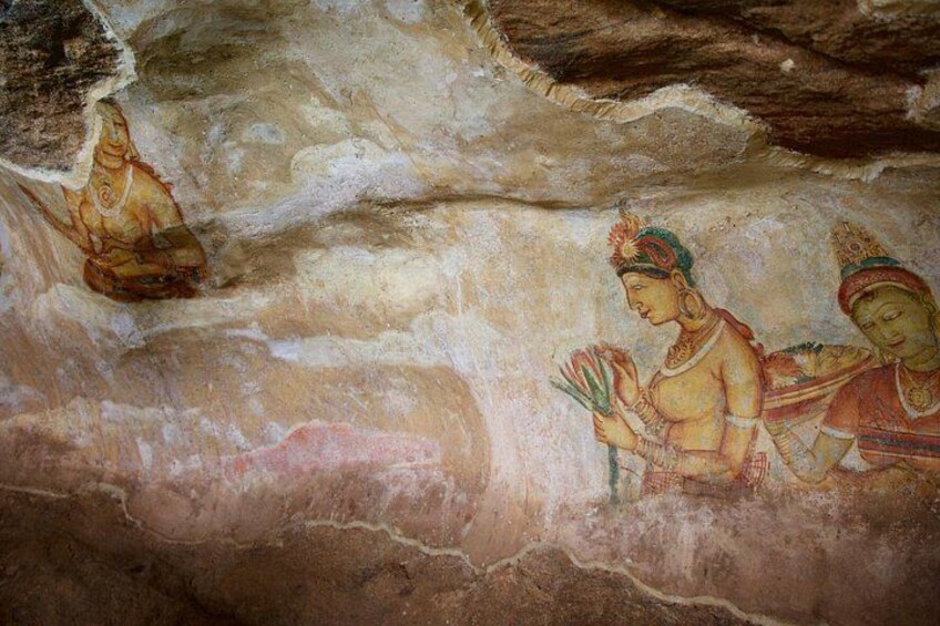 Una cueva con frescos antiguos que muestran figuras vestidas con atuendos tradicionales. 4