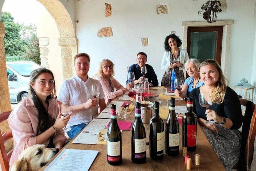 Un groupe de personnes est assis autour d’une table, devant des bouteilles de vin et des verres. 1