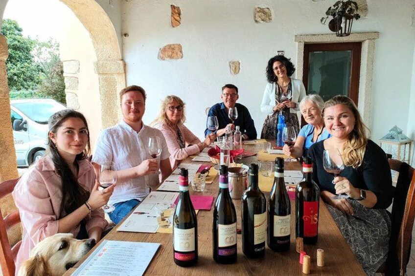 A group of people sitting around a table with wine bottles and glasses. 1