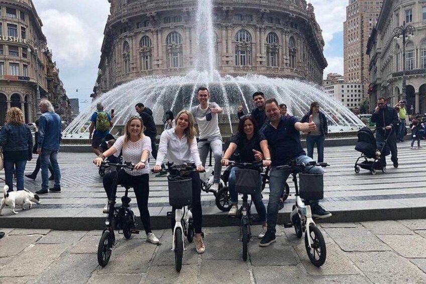 Des personnes à vélo devant une fontaine, avec un bâtiment historique en arrière-plan. 5