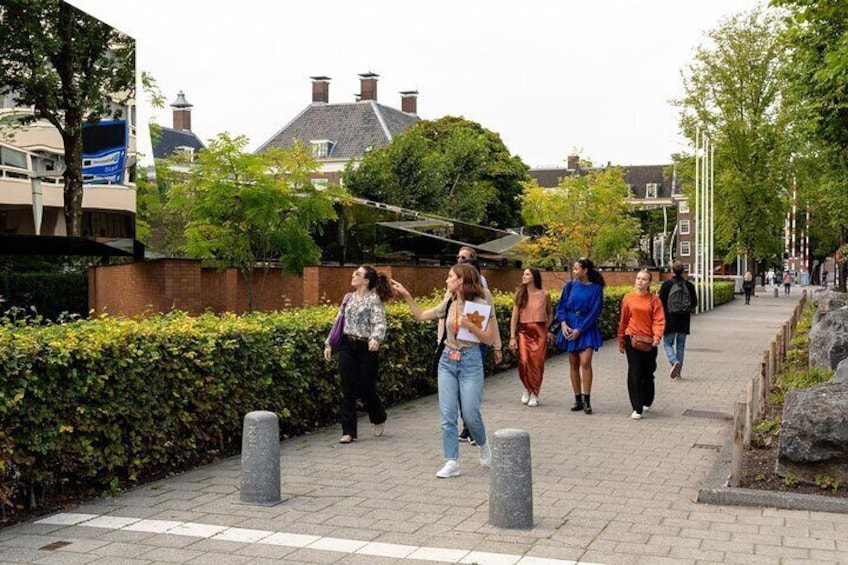 A group of people walking on a paved path in a park with trees and buildings in the background. 4