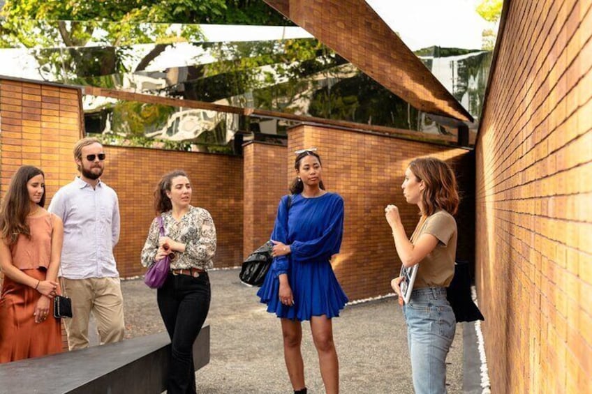 A group of people standing on a sidewalk near a brick wall. 5
