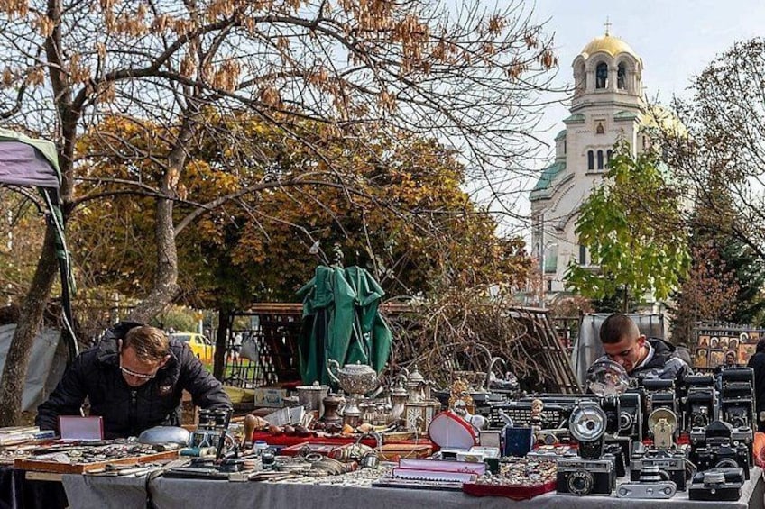 Un mercado de pulgas con objetos antiguos e iglesia al fondo. 1