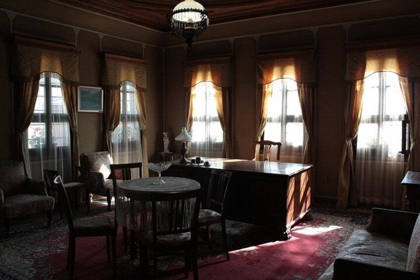 A room with a round table, chairs, and a desk. 4