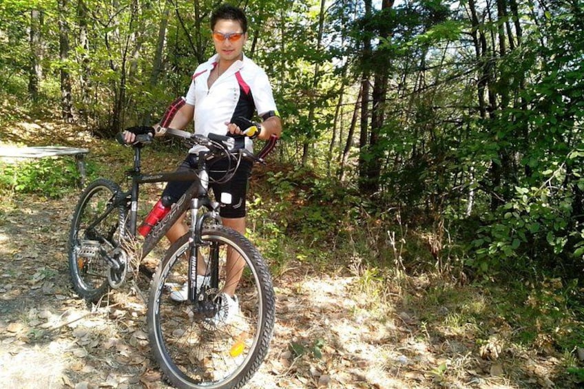 A person on a mountain bike in a forested area with a trail. 2