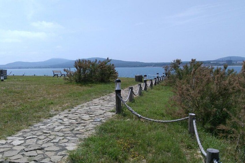 A stone pathway leading to a lake, with a bench and a rope barrier along the path. 5