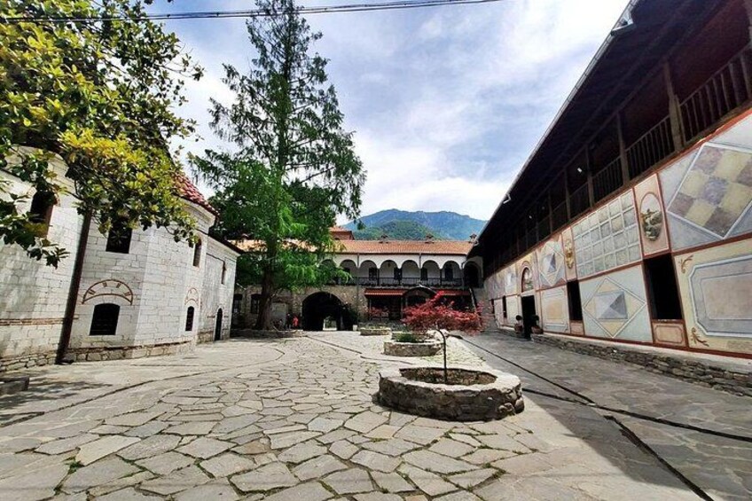 Un patio con pavimento de piedra, un árbol y un edificio con ventanas de arco. 5
