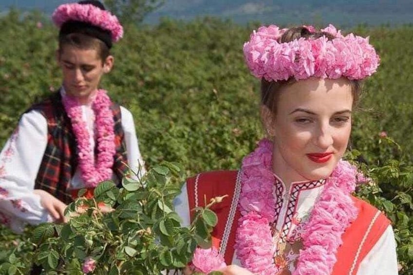 Two individuals in traditional attire with floral headpieces in a field of greenery. 4