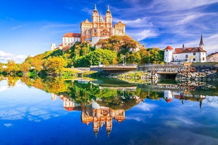 A historic castle on a hill with a clear reflection in the water. 1