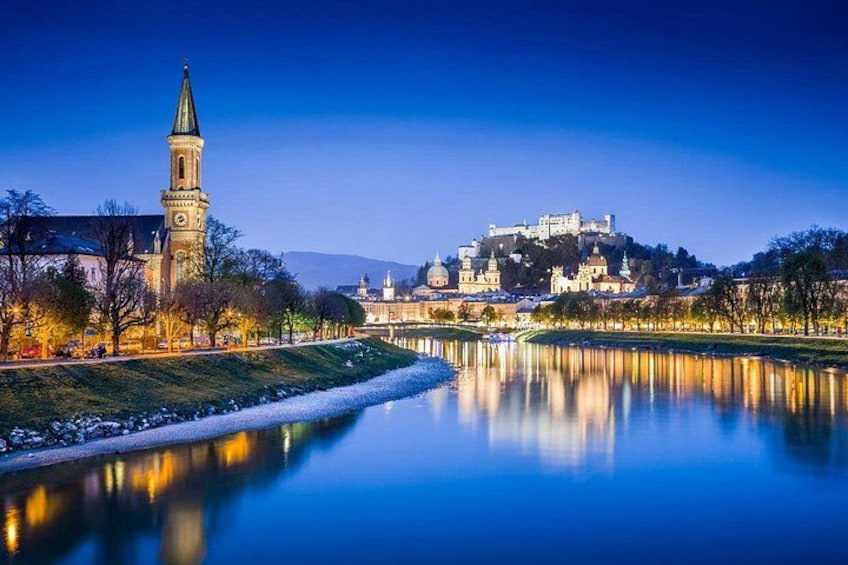 A calm river reflecting a historic castle and a church with a tall tower. 3