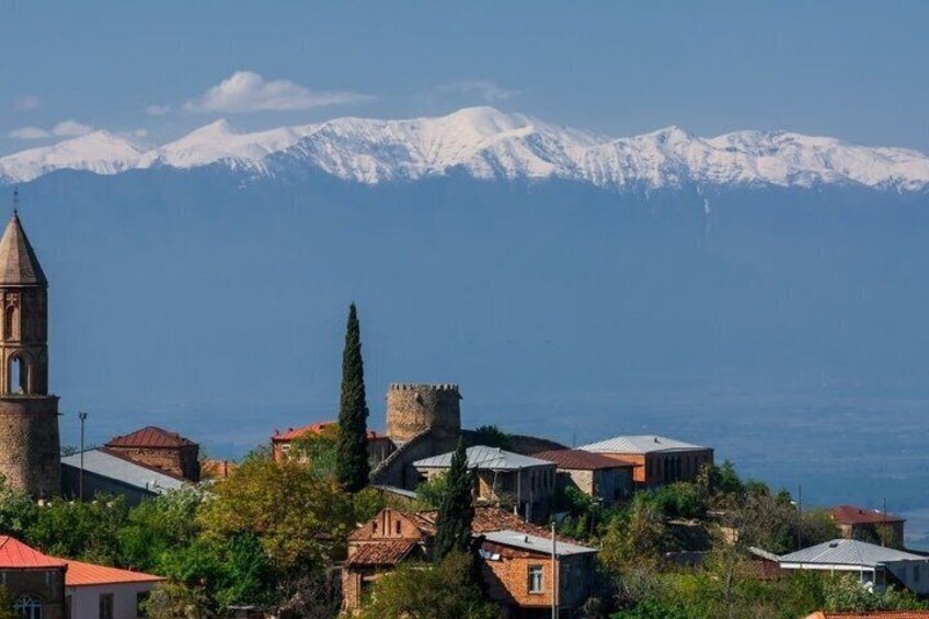 Un pueblo costero con una iglesia, un castillo y montañas nevadas al fondo. 2