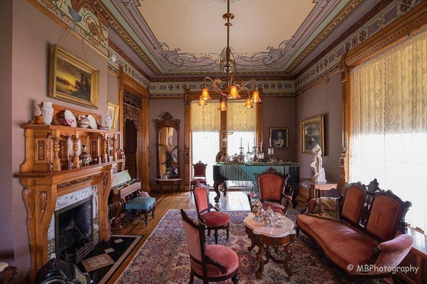 A grand room with ornate furniture, a fireplace, and a chandelier. 3