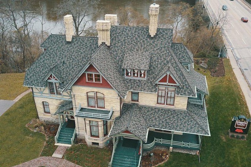A large, two-story house with a steeply pitched roof, multiple chimneys, and a front porch. 4