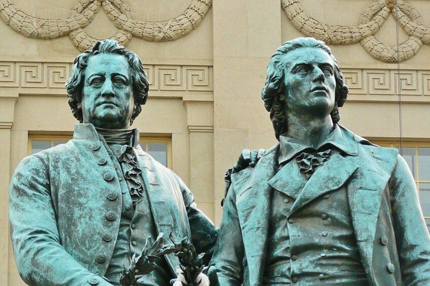 Una estatua de un hombre con uniforme militar y espada, frente a un edificio con detalles arquitectónicos clásicos. 2