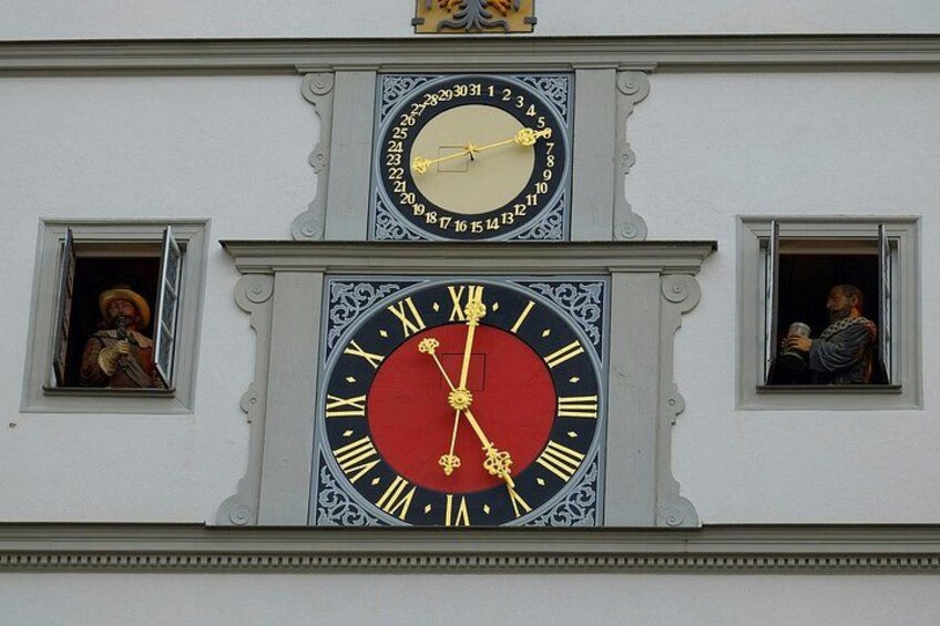 Ein Gebäude mit zwei Uhren übereinander und zwei kleinen Fenstern mit Statuen. 2