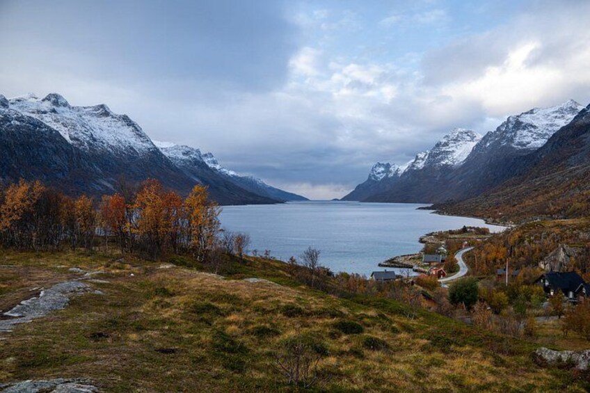 A mountainous landscape with a lake, autumn trees, and a small settlement. 3