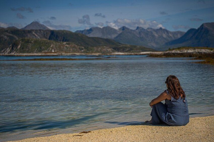 A person sitting by a lake with mountains in the background. 5