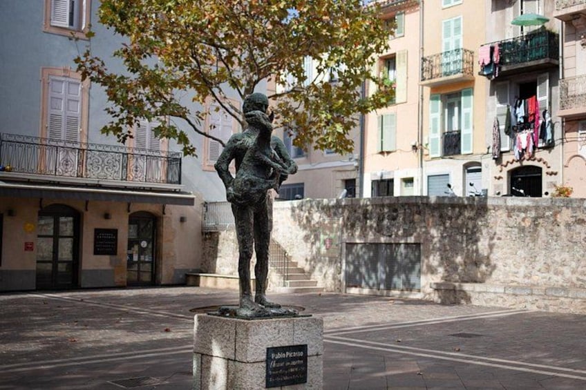 Een standbeeld van een man in een park, met gebouwen op de achtergrond. 5