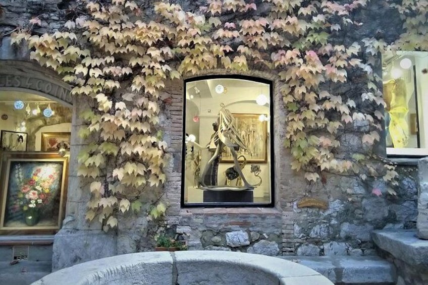 A building facade with a statue in a window, surrounded by ivy. 3
