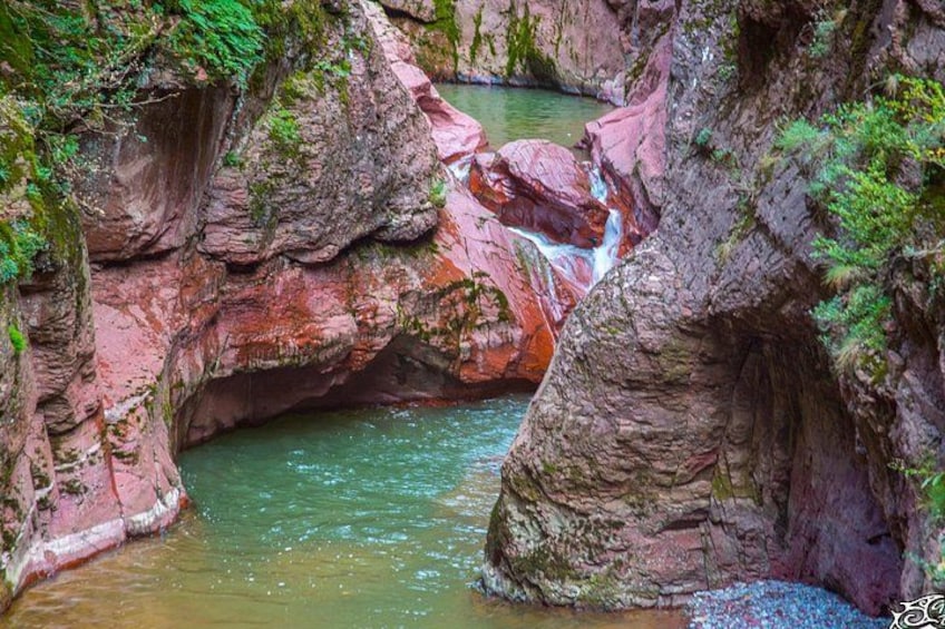 Un cañón rocoso con una cascada y un río. 1
