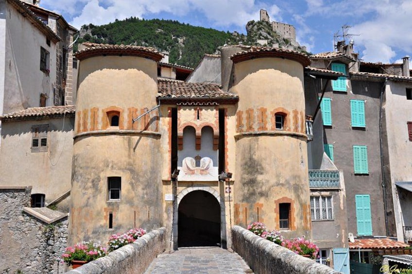 Un edificio histórico con un arco central, flanqueado por dos torres cilíndricas, y un sendero de piedra que conduce a la entrada. 4