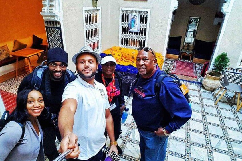 A group of people taking a selfie in a courtyard with patterned tiles and traditional Moroccan architecture. 2