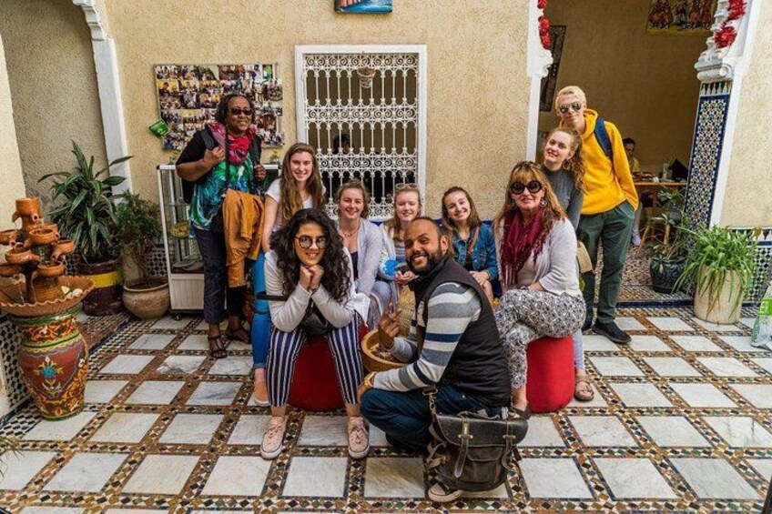 A group of people posing on a tiled patio with potted plants and a decorative gate. 3