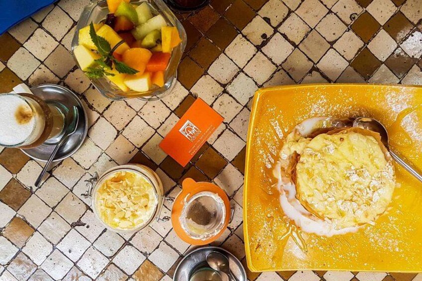 Un suelo de baldosas con un frutero, un plato amarillo con comida, un vaso de bebida y un pequeño recipiente. 3