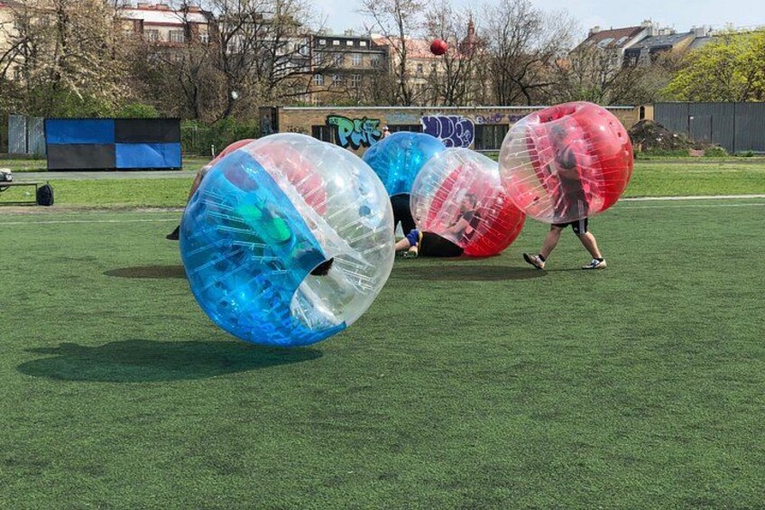 Mensen spelen met grote opblaasbare ballen op een grasveld. 2