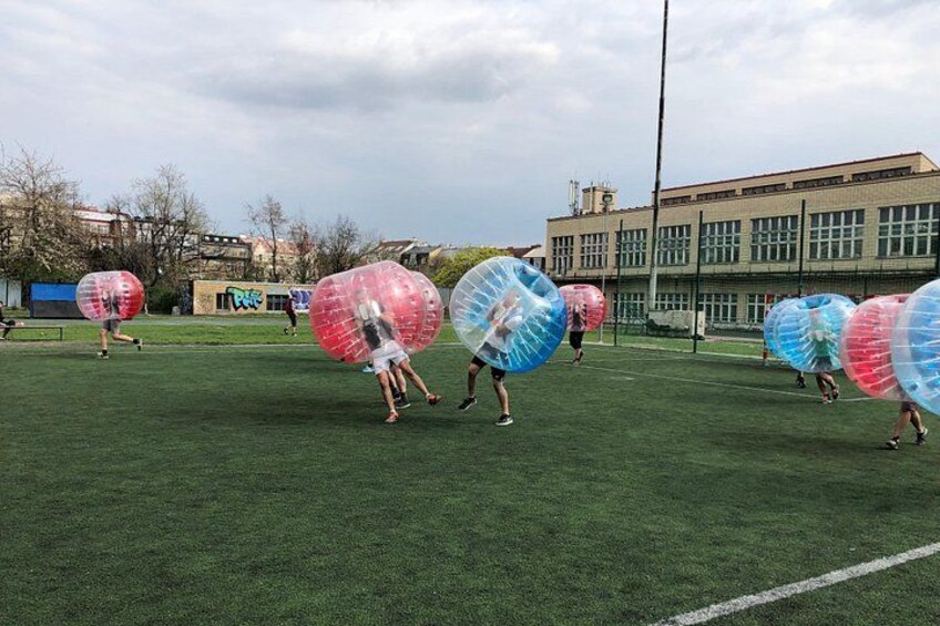 Mensen spelen met grote opblaasbare ballen op een grasveld. 4