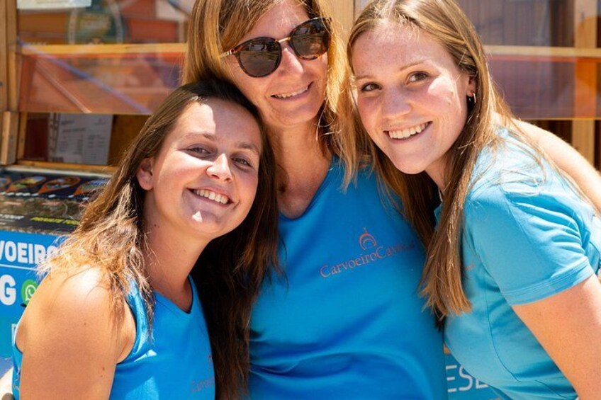 Three people wearing blue shirts with logos, standing in front of a shop with a sign. 2