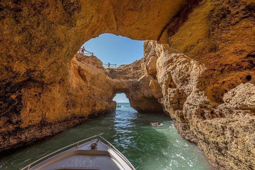 A boat navigating through a natural rock arch formation with a clear view of the sea beyond. 5