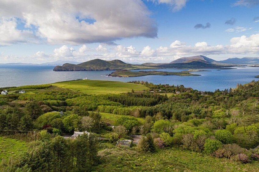 A coastal landscape with rolling hills, a body of water, and distant mountains. 3
