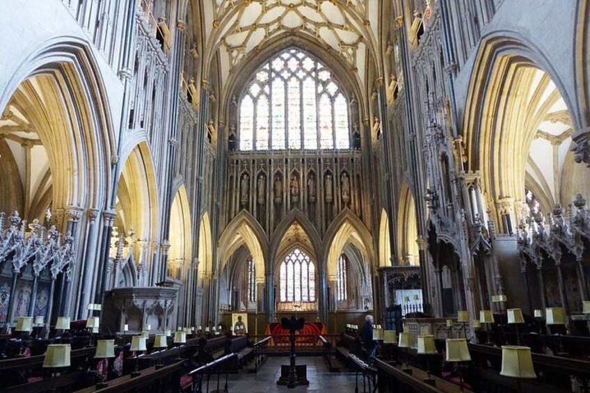 A cathedral interior with high vaulted ceilings, stained glass windows, and rows of pews. 1