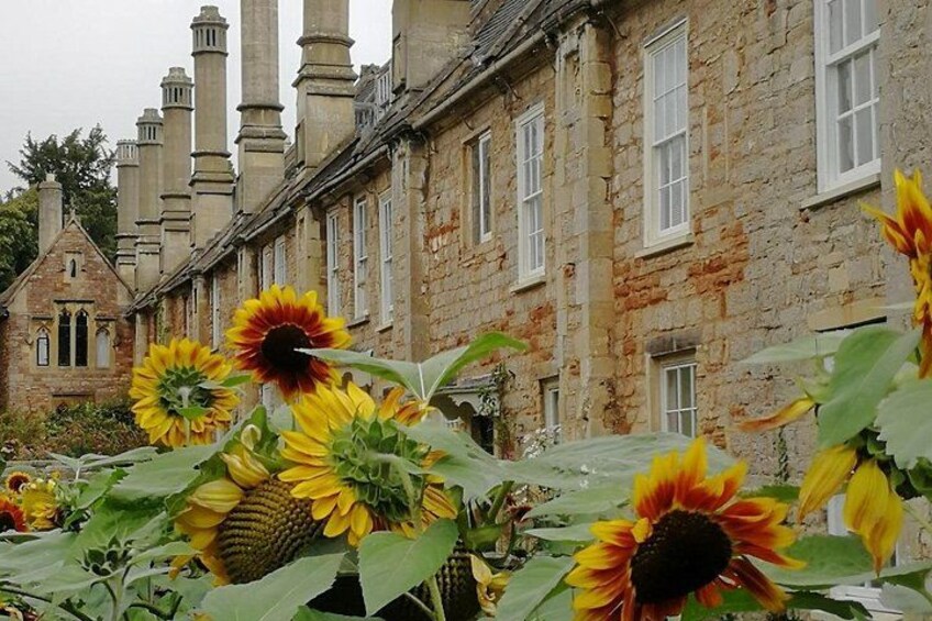 A row of stone buildings with multiple chimneys, surrounded by sunflowers. 4