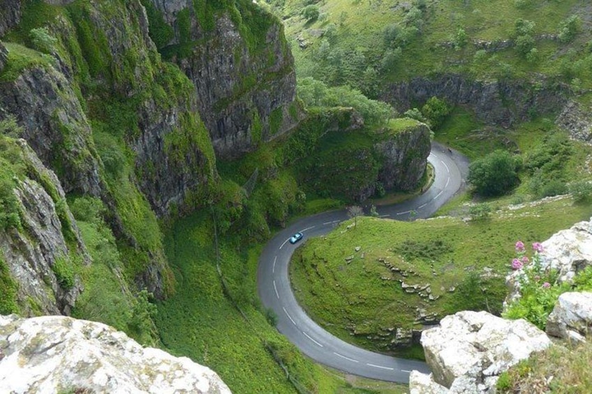 Une route de montagne sinueuse, bordée d’une végétation luxuriante et de falaises rocheuses. 1