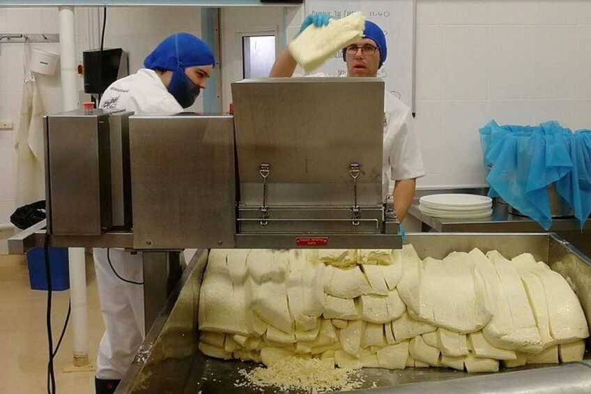 Une usine de transformation alimentaire où des employés manipulent de gros blocs de fromage. 5