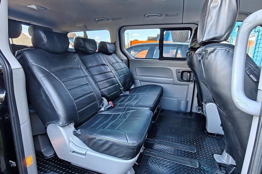 A vehicle interior with black leather seats, a center console, and a rearview mirror. 4
