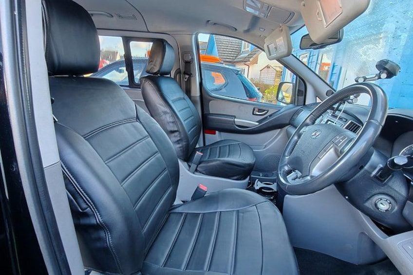 A car interior with black leather seats, a steering wheel, and a dashboard. 3