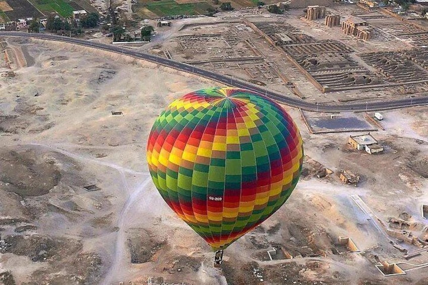 A hot air balloon over a construction site with visible buildings and roads. 4