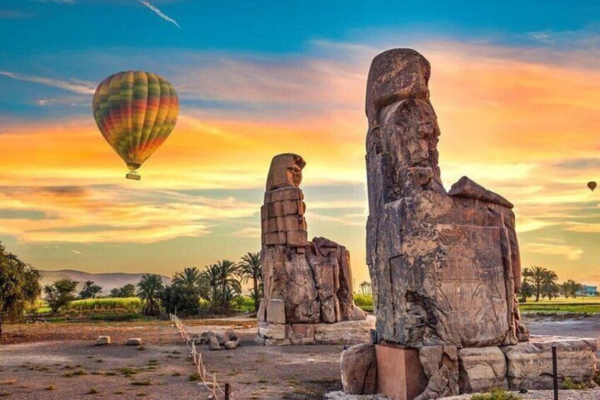 Ancient Egyptian statues, a hot air balloon, and a sunset sky. 3