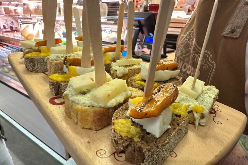 A wooden board with various food items, including bread, cheese, and possibly meat, arranged for display. 1