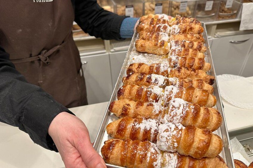 En bakke med kager, sandsynligvis croissanter, drysset med flormelis. 4