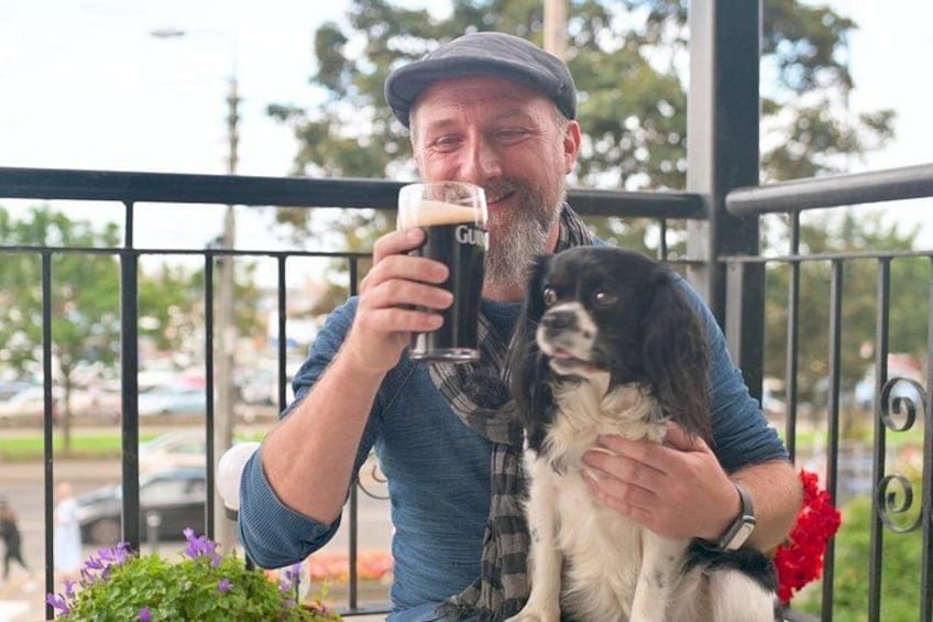 Iemand houdt een hond en een biertje vast op een balkon. 1