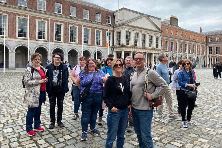 Un grupo de personas de pie en un patio empedrado con edificios históricos al fondo. 3