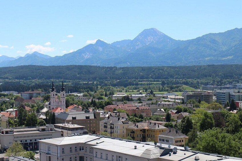 En stad med en framträdande kyrka, vackra byggnader och berg i bakgrunden. 3