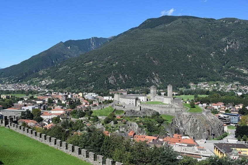 Un pueblo con un castillo, colinas verdes y un cielo despejado. 2