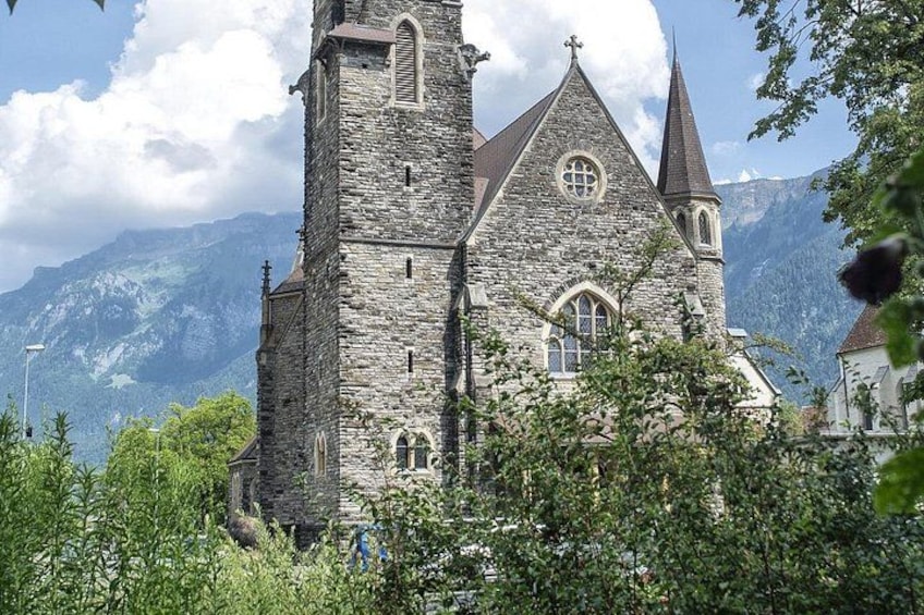 Una chiesa in pietra con un alto campanile e montagne sullo sfondo. 4