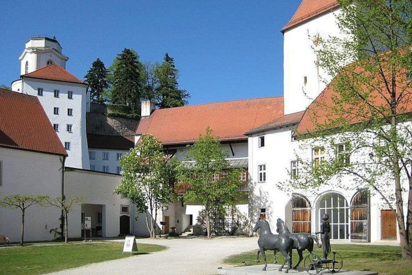 A courtyard with white buildings, a statue of a horse and rider, and a clear blue sky. 3